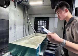 CNC engineer inspecting aluminum part machining process in a precision workshop