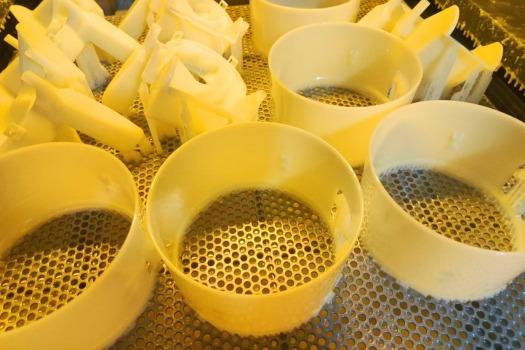 3D printing prototypes of plastic parts being cured after printing, showcasing high-precision additive manufacturing at TiRapid.