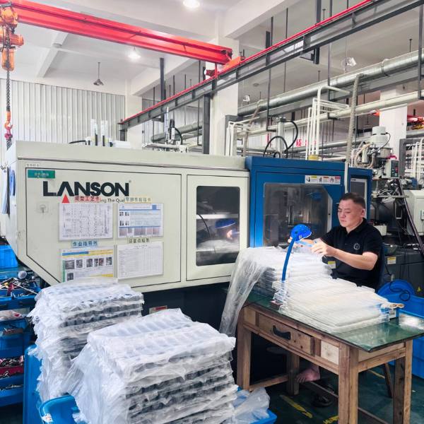 Plastic injection moulding services – worker assembling moulded parts beside injection moulding machine, surrounded by finished components