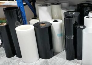 Comparison of acetal and Delrin plastic rolls in black and white, used for machining