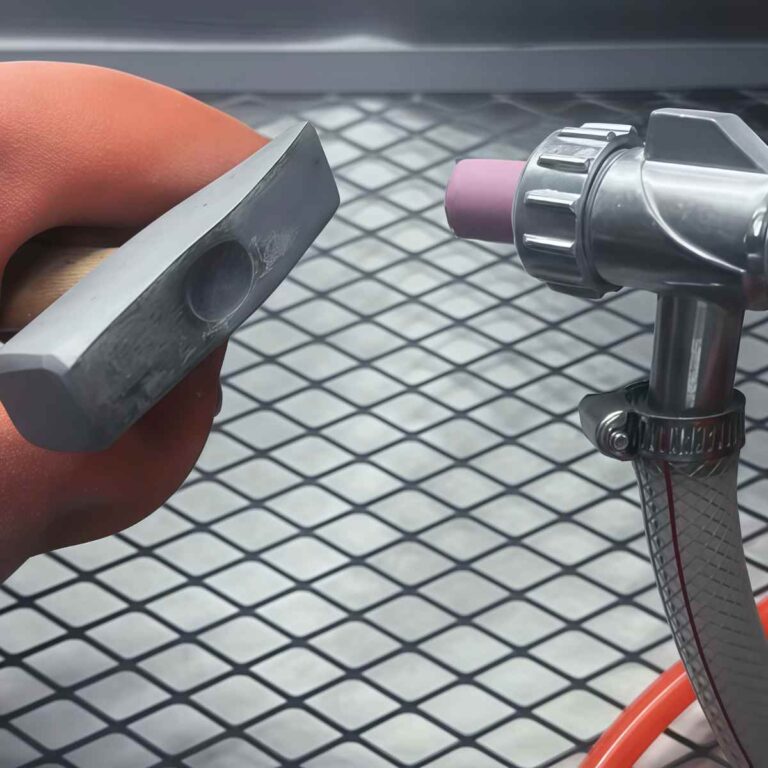 Close-up view of bead blasting nozzle treating a metal surface with fine abrasive media