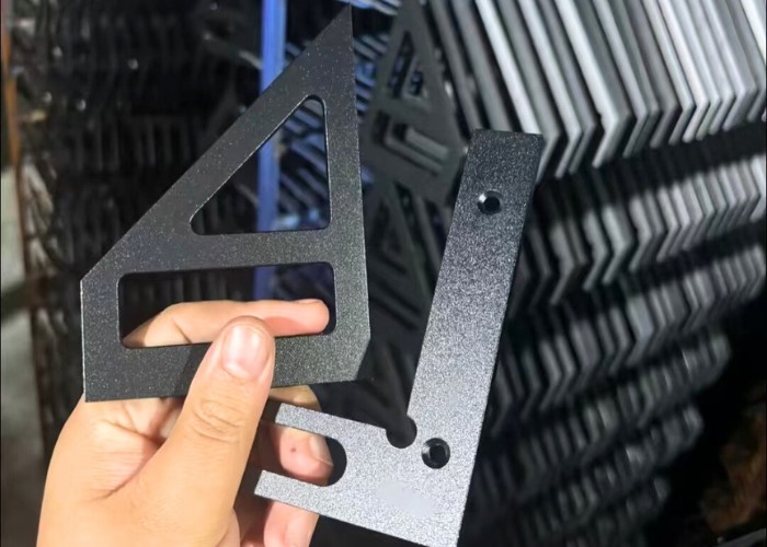 Black anodized aluminum parts being processed in a CNC machining workshop, showing textured surface finish and batch production capability.