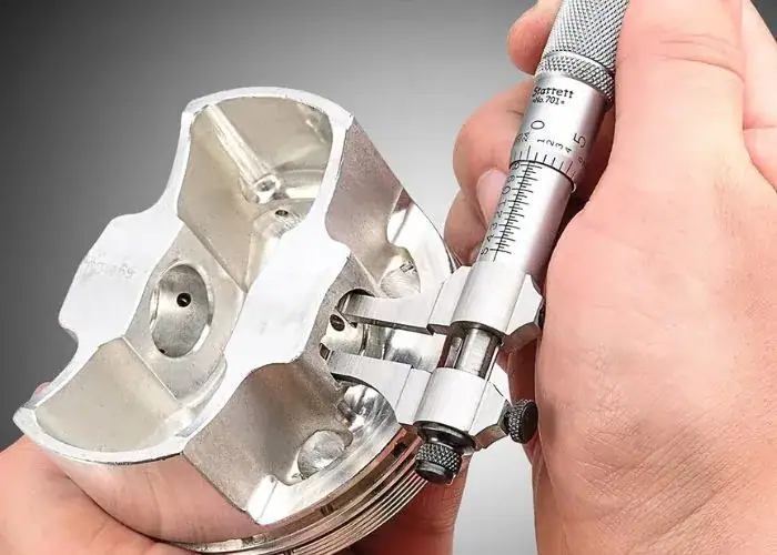 Outside micrometer measuring a precision CNC machined metal component for dimensional accuracy