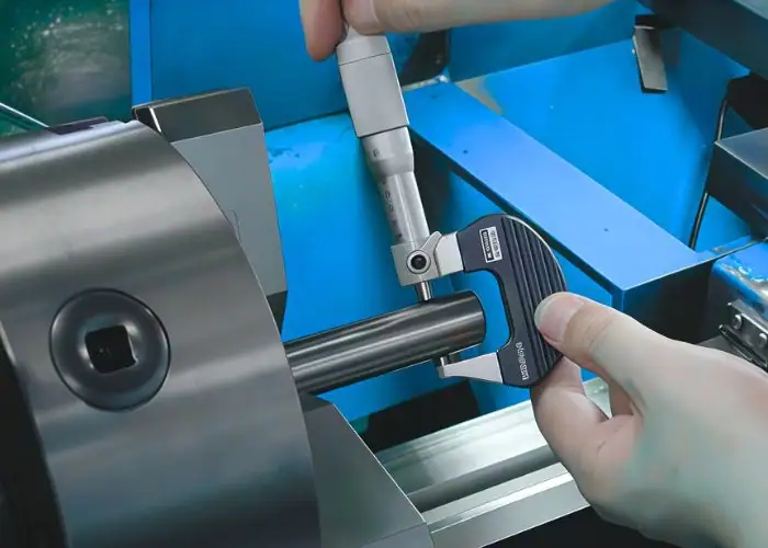 machinist measuring shaft diameter using an outside micrometer in cnc inspection
