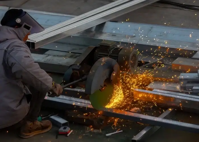Worker cutting metal using angle grinder producing sparks