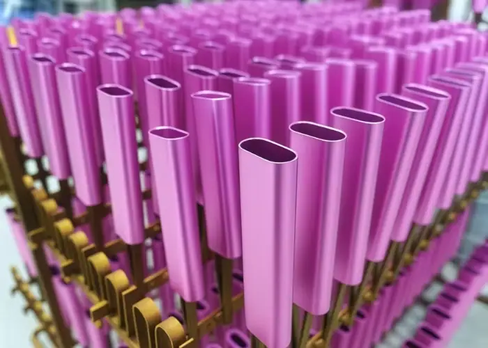 Pink anodized aluminum tubes arranged on a production rack after anodizing treatment