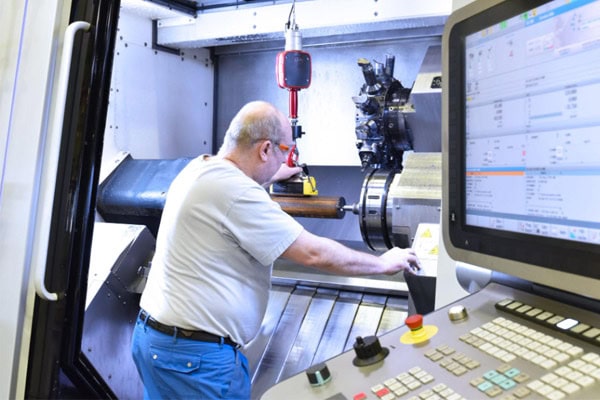 Image of a technician operating a CNC turn-mill machine,