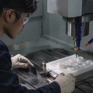 Workers are performing CNC machining on PTFE plastic material