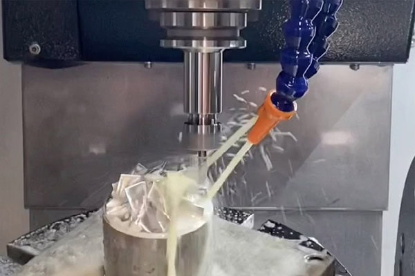 Five-axis machining center sprays cutting fluid into the cutting zone.