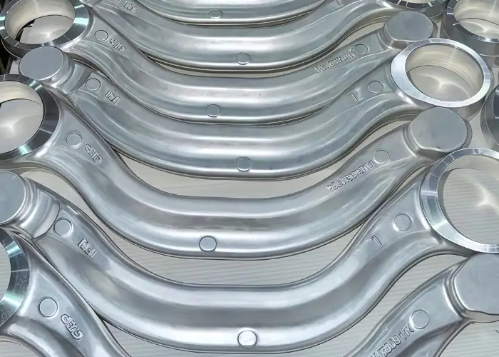 Multiple 6082 aluminum forged suspension control arms with machined mounting holes for automotive chassis applications.