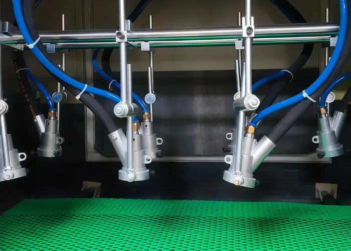 Automatic multi-gun conveyor bead blasting machine processing aluminum workpieces to produce a uniform matte surface finish in a metal finishing production line.
