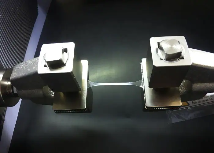 Ultimate tensile strength plastic testing showing a specimen under tensile load before failure