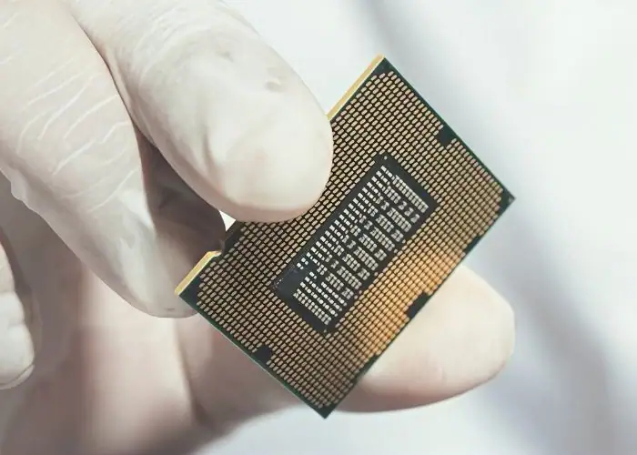 Close‑up of finished packaged IC chip for semiconductor manufacturing held in gloved hand